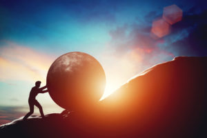 An Impact Trailblazer research image of a person pushing a boulder up a hill.