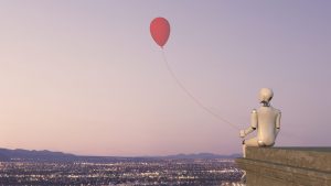 A white robot is sitting on the rooftop ledge of a building with the view of a city with lights, holding a red balloon. Business Impact article on Top tips to be a better daydreamer — and how it will help you.