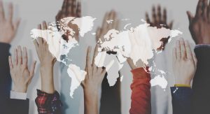 Hands up in the air against a map of the world. Business Impact article for today's education: global commodity and catalyst for cultural diversity