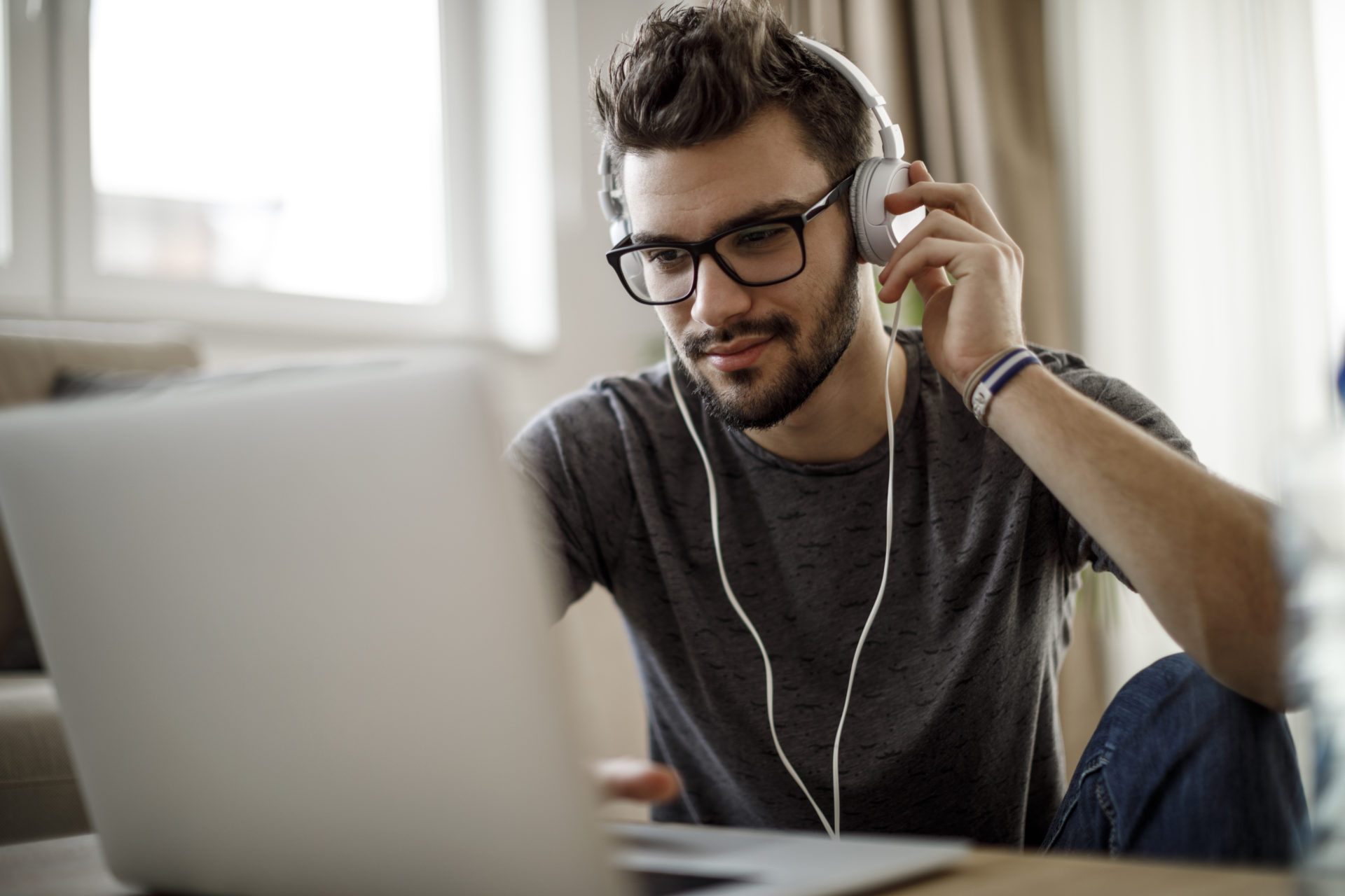 A young male student studying at home and listening to music.