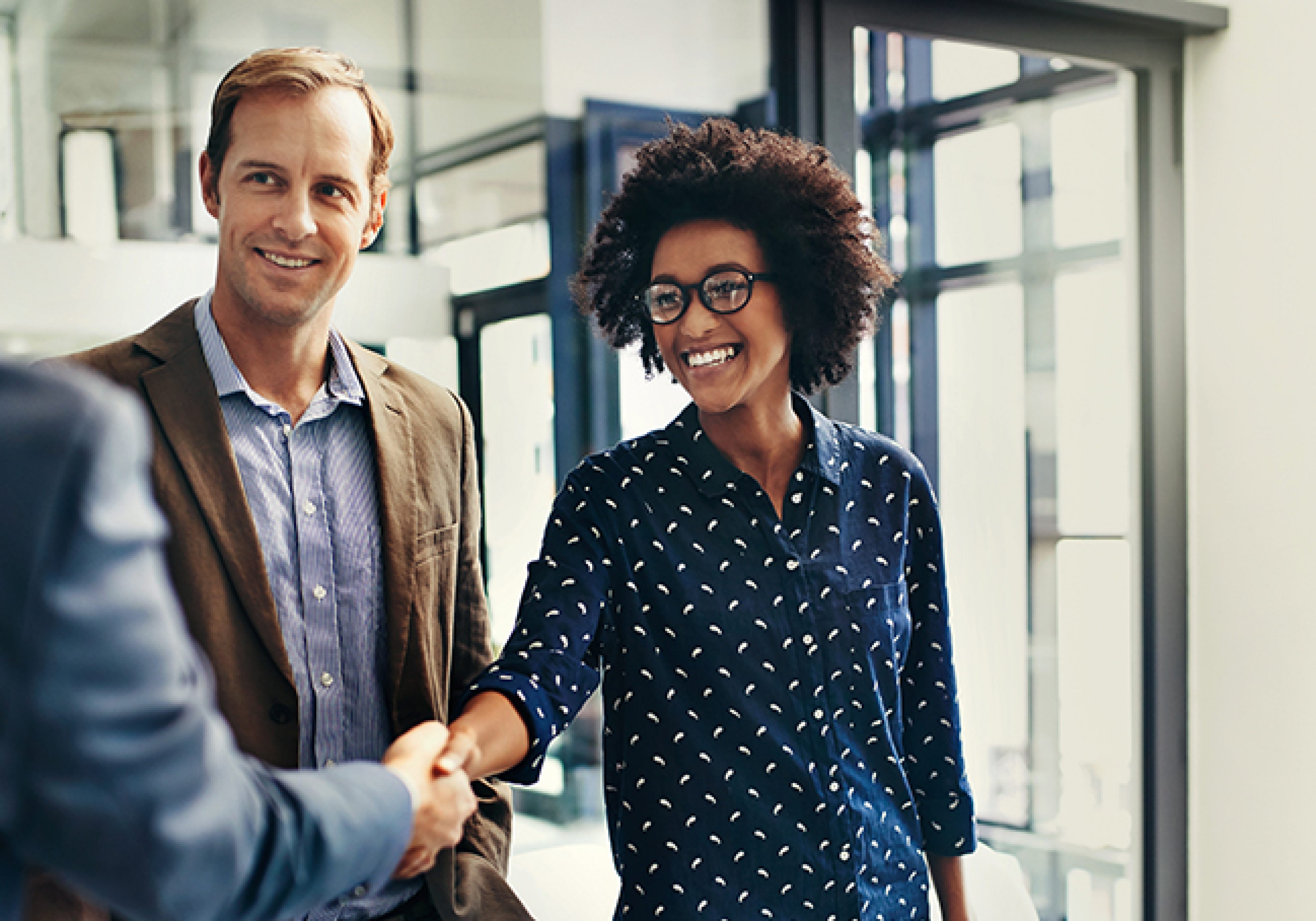 Shot of colleagues shaking hands during a meeting at work