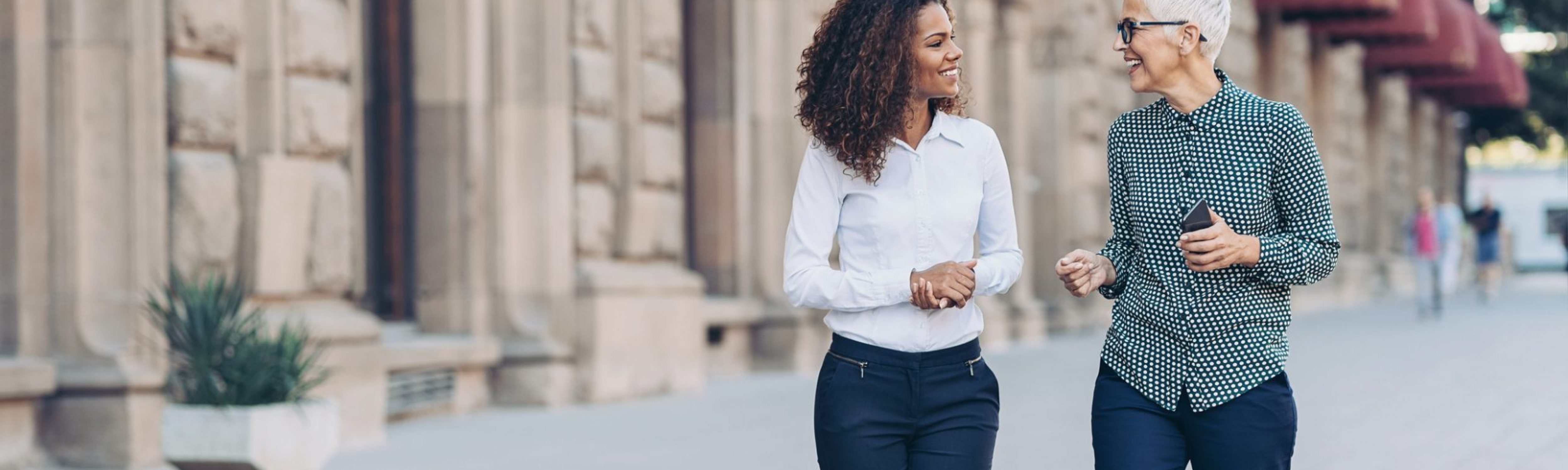 Two female business professional leaders engaged in a conversation and socialising.