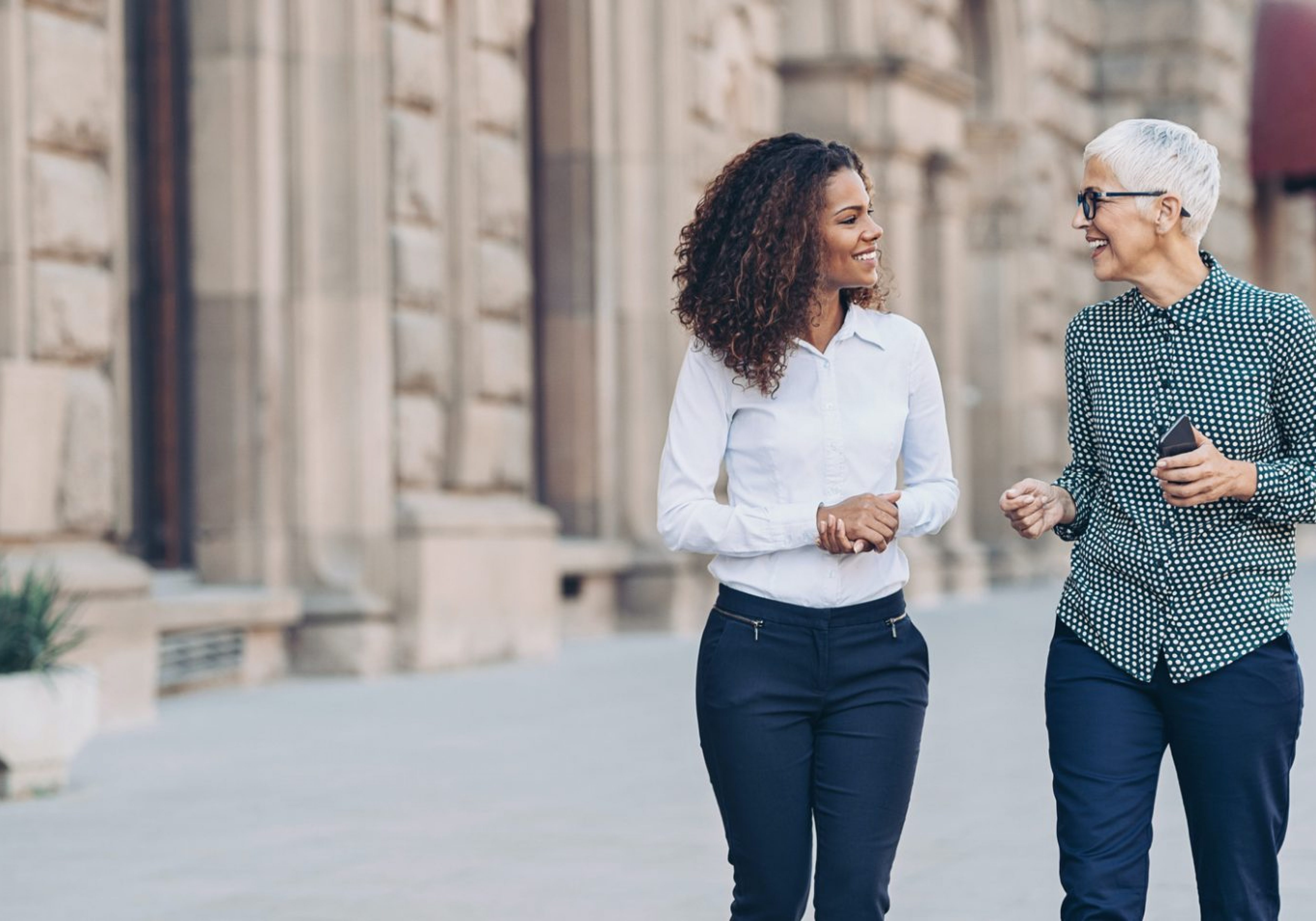 Two female business professional leaders engaged in a conversation and socialising.