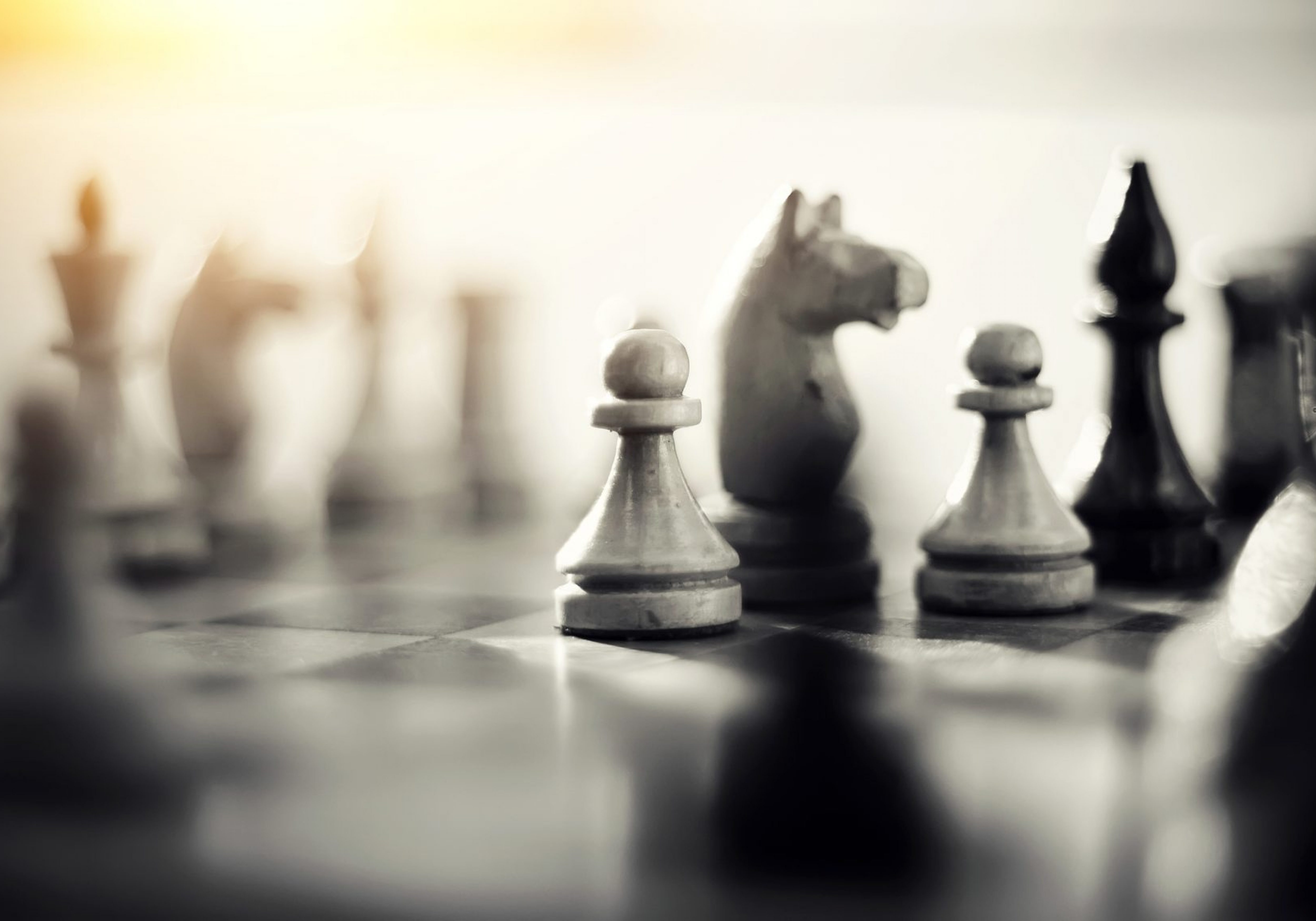 Close up of a black and white chess game focusing on the pawns and the knights is symbolic to taking charge, planning, strategy, and challenge.