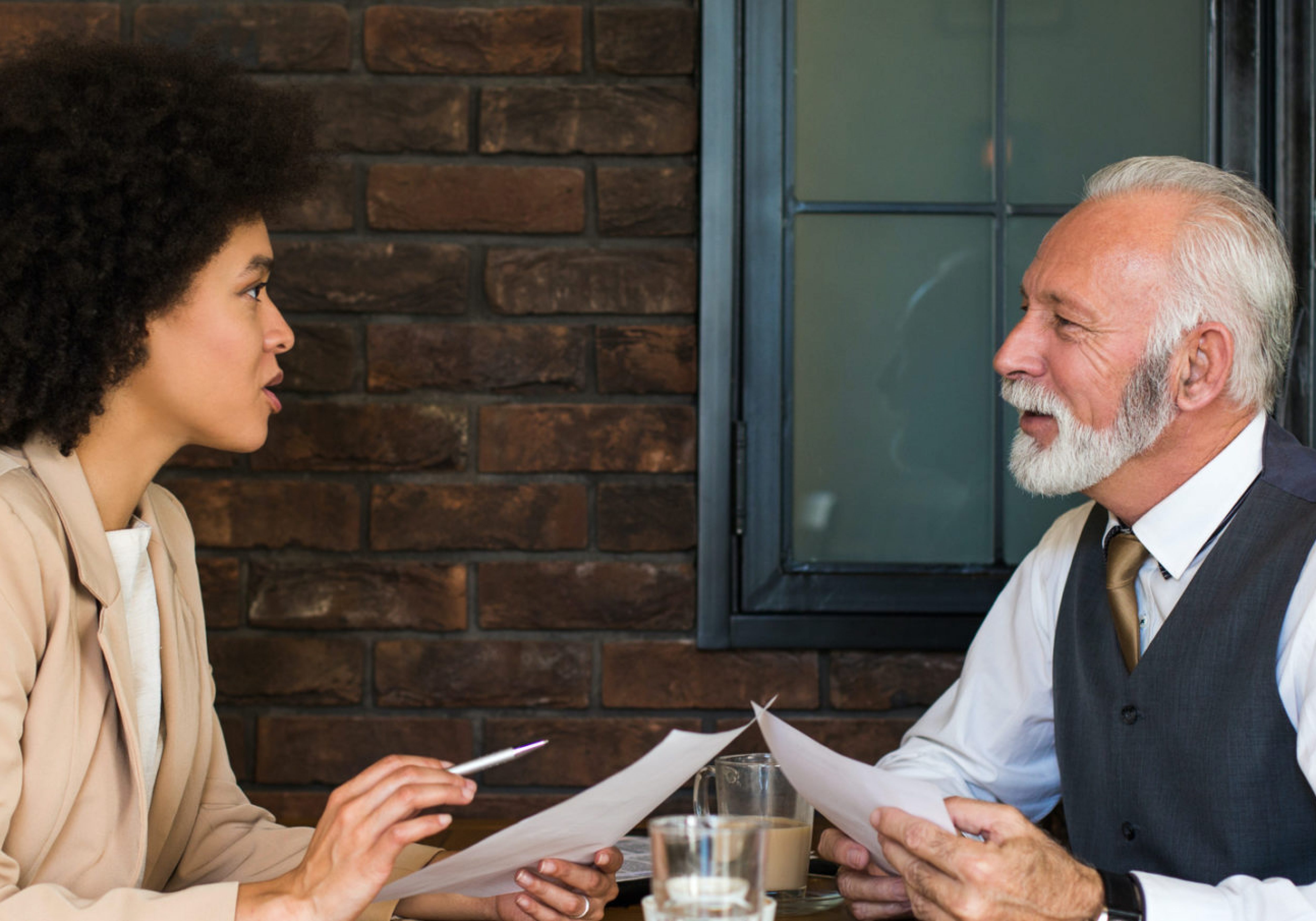 Business man and woman reviewing some documents. Business Impact article image for how to get reverse mentoring right — and why it's key to tackling diversity.